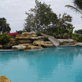 Idéer för en stor exotisk infinitypool på baksidan av huset, med naturstensplattor och vattenrutschkana