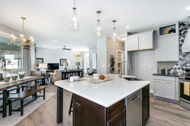 Large contemporary l-shaped eat-in kitchen in Wichita with a farmhouse sink, quartz benchtops, multi-coloured splashback, ceramic splashback, stainless steel appliances, with island, brown floor, shaker cabinets, grey cabinets and medium hardwood floors.