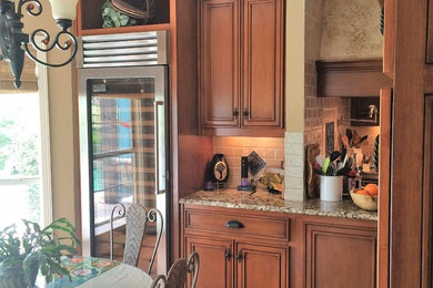 Photo of a mid-sized traditional u-shaped eat-in kitchen in Dallas with recessed-panel cabinets, medium wood cabinets, granite benchtops, beige splashback, ceramic splashback, panelled appliances, medium hardwood floors, with island and brown floor.