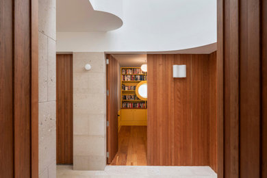 Esempio di un ingresso o corridoio minimalista di medie dimensioni con pareti beige, pavimento in pietra calcarea, pavimento beige e pannellatura