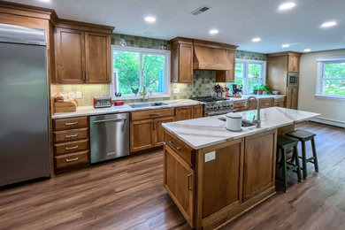 Eat-in kitchen - large transitional single-wall vinyl floor and brown floor eat-in kitchen idea in Cleveland with an undermount sink, raised-panel cabinets, medium tone wood cabinets, green backsplash, porcelain backsplash, stainless steel appliances, an island and multicolored countertops