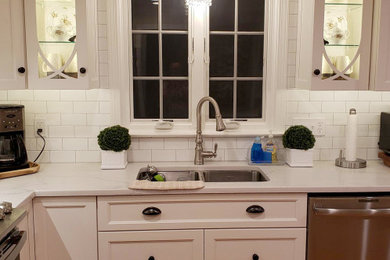Immagine di una cucina con lavello a doppia vasca, ante bianche, top in quarzo composito, paraspruzzi bianco, paraspruzzi con piastrelle diamantate, elettrodomestici in acciaio inossidabile e top bianco
