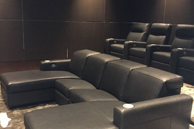 This is an example of a modern enclosed home theatre in Dallas with black walls and carpet.