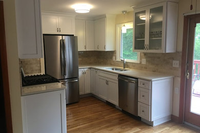 Example of a small transitional u-shaped light wood floor eat-in kitchen design in Providence with an undermount sink, shaker cabinets, white cabinets, quartz countertops, beige backsplash, marble backsplash, stainless steel appliances, no island and beige countertops