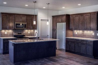 Eat-in kitchen - mid-sized l-shaped eat-in kitchen idea in Other with a double-bowl sink, shaker cabinets, brown cabinets, granite countertops, stone tile backsplash, stainless steel appliances, an island and multicolored countertops
