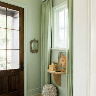 Small eclectic foyer in Nashville with green walls, light hardwood floors and a single front door.