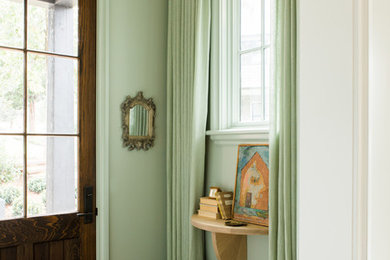 Small eclectic foyer in Nashville with green walls, light hardwood floors and a single front door.