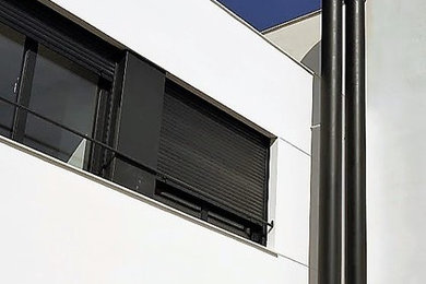 Foto de fachada de casa blanca moderna de tamaño medio de dos plantas con revestimiento de aglomerado de cemento, tejado plano y tejado de varios materiales