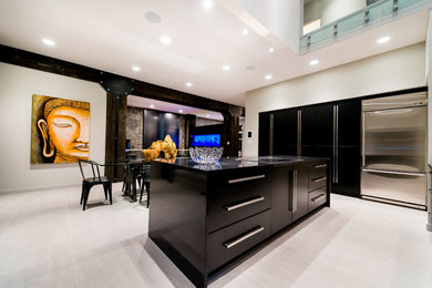 Open concept kitchen - large modern l-shaped light wood floor and beige floor open concept kitchen idea in Other with stainless steel appliances, an island, an undermount sink, flat-panel cabinets, black cabinets, quartzite countertops, gray backsplash, glass sheet backsplash and black countertops