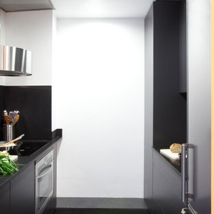 Idées déco pour une petite arrière-cuisine linéaire contemporaine avec un évier encastré, un placard à porte plane, des portes de placard noires, un plan de travail en granite, une crédence noire, une crédence en pierre calcaire, un électroménager en acier inoxydable, un sol en calcaire et un sol gris.