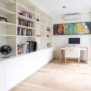 Photo of a contemporary study room in Sydney with white walls, light hardwood floors, a freestanding desk and beige floor.