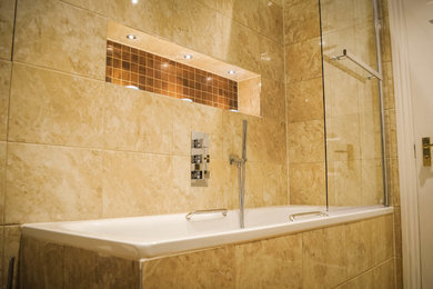 Medium sized contemporary family bathroom in London with beige tiles, a built-in bath, a shower/bath combination, porcelain tiles and beige walls.