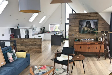 Large modern l-shaped open plan kitchen in Kent with a single-bowl sink, flat-panel cabinets, white cabinets, engineered stone countertops, white splashback, ceramic splashback, integrated appliances, light hardwood flooring, an island, brown floors and grey worktops.