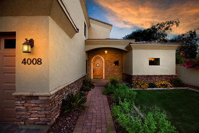 Inspiration for a large mediterranean beige two-story stone house exterior remodel in Phoenix with a hip roof and a shingle roof