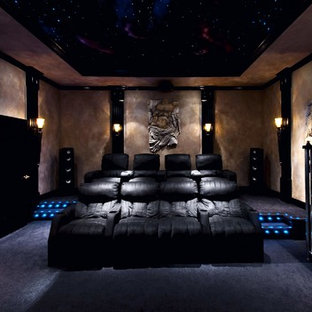 This is an example of a large modern enclosed home cinema in Atlanta with brown walls, carpet, a projector screen and blue floors.