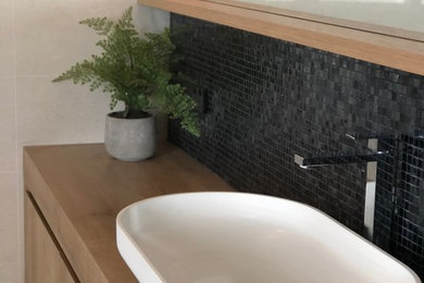 Design ideas for a modern master bathroom in Townsville with furniture-like cabinets, light wood cabinets, multi-coloured tile, mosaic tile and laminate benchtops.