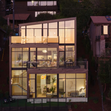 Bay-facing rear exterior with full-height glazing at sunset - Fold House