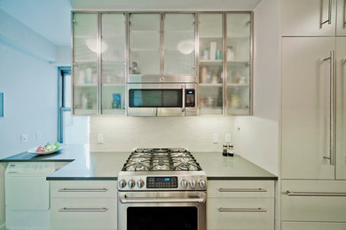 Design ideas for a small contemporary galley separate kitchen in New York with an undermount sink, glass-front cabinets, white cabinets, solid surface benchtops, white appliances, dark hardwood floors, no island and brown floor.