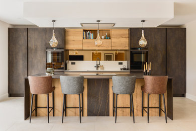 Large contemporary cream and black single-wall kitchen/diner in Surrey with a submerged sink, flat-panel cabinets, distressed cabinets, engineered stone countertops, brown splashback, mirror splashback, black appliances, porcelain flooring, an island, beige floors, black worktops, a drop ceiling and feature lighting.