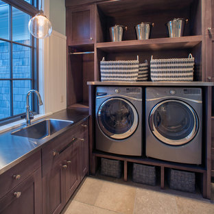 Modelo de lavadero en L, clásico renovado, grande, con armarios estilo shaker, puertas de armario de madera en tonos medios, suelo de baldosas de cerámica, lavadora y secadora juntas, suelo beige, paredes verdes, encimera de acero inoxidable y encimeras grises