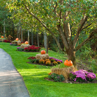 This is an example of a traditional front yard driveway for fall in Boston with with flowerbed.