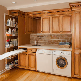Foto de lavadero multiusos y lineal, clásico, pequeño, con fregadero de un seno, armarios con paneles con relieve, encimera de mármol, suelo de madera clara, lavadora y secadora juntas y puertas de armario de madera oscura