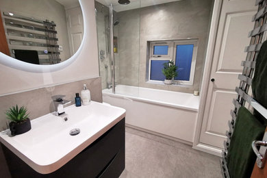 Inspiration for a medium sized contemporary grey and white family bathroom in West Midlands with black cabinets, a built-in bath, a shower/bath combination, a one-piece toilet, grey tiles, ceramic tiles, grey walls, vinyl flooring, grey floors, a wall niche, a single sink and a floating vanity unit.