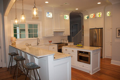Example of a large classic l-shaped dark wood floor open concept kitchen design in Jackson with a farmhouse sink, raised-panel cabinets, white cabinets, marble countertops, white backsplash, subway tile backsplash, stainless steel appliances and an island