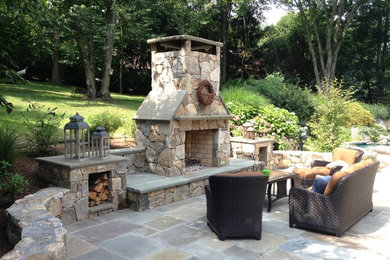 Example of a mid-sized classic backyard stone patio design in New York with a fire pit and no cover