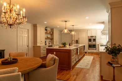 Eat-in kitchen - medium tone wood floor eat-in kitchen idea in Cleveland with an undermount sink, shaker cabinets, white cabinets, quartz countertops, beige backsplash, an island and white countertops
