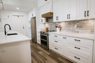 Example of an eat-in kitchen design in Vancouver with recessed-panel cabinets, white cabinets, quartzite countertops, gray backsplash, brick backsplash, an island and white countertops