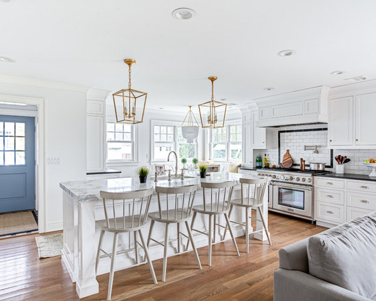 Transitional open concept kitchen pictures - Example of a transitional galley medium tone wood floor and brown floor open concept kitchen design in New York with an undermount sink, shaker cabinets, white cabinets, white backsplash, subway tile backsplash, stainless steel appliances and an island