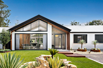 Expansive contemporary one-storey white house exterior in Central Coast with a metal roof and a white roof.