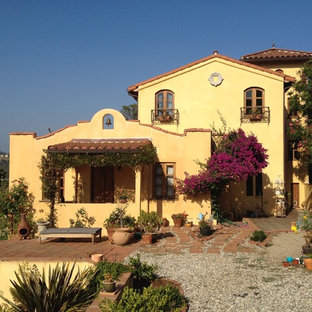 ロサンゼルスのサンタフェスタイルのおしゃれな家の外観 (漆喰サイディング、黄色い外壁、瓦屋根、切妻屋根、戸建) の写真