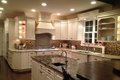 Large elegant l-shaped medium tone wood floor eat-in kitchen photo in Philadelphia with an undermount sink, raised-panel cabinets, beige cabinets, granite countertops, multicolored backsplash, mosaic tile backsplash, paneled appliances and an island