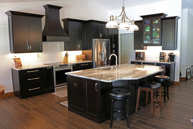 Open concept kitchen - transitional medium tone wood floor open concept kitchen idea in Tampa with a single-bowl sink, raised-panel cabinets, dark wood cabinets, granite countertops, white backsplash, subway tile backsplash, stainless steel appliances and an island