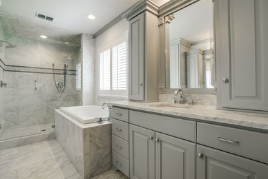 This is an example of a large traditional master bathroom in Dallas with an undermount sink, raised-panel cabinets, grey cabinets, marble benchtops, an undermount tub, an alcove shower, a one-piece toilet, white walls, gray tile, marble, marble floors, grey floor and a hinged shower door.