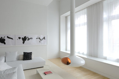Photo of a scandinavian living room in New York with white walls, light hardwood floors and a hanging fireplace.
