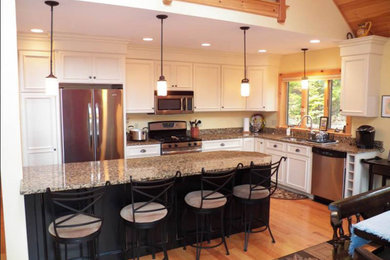 Inspiration for a mid-sized timeless light wood floor kitchen remodel in Portland with a drop-in sink, white cabinets, granite countertops, stainless steel appliances and an island
