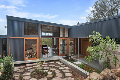 Photo of a large modern two-storey multi-coloured house exterior in Brisbane with metal siding, a flat roof and a metal roof.