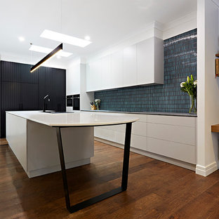 Photo of a single-wall kitchen pantry in Melbourne with a drop-in sink, beaded inset cabinets, white cabinets, marble benchtops, subway tile splashback, black appliances, plywood floors and with island.
