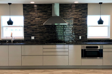 Eat-in kitchen - modern l-shaped porcelain tile and brown floor eat-in kitchen idea in Orlando with an undermount sink, flat-panel cabinets, beige cabinets, quartzite countertops, multicolored backsplash, glass tile backsplash, stainless steel appliances and brown countertops