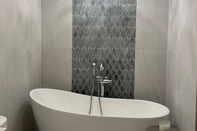 Ejemplo de cuarto de baño de pie moderno pequeño con puertas de armario blancas, bañera exenta, baldosas y/o azulejos grises, baldosas y/o azulejos de porcelana, paredes grises y suelo gris
