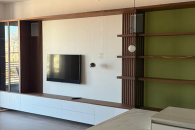 Esempio di un ampio soggiorno design aperto con libreria, pareti verdi, parquet scuro e TV a parete
