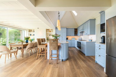 This is an example of a large beach style kitchen/diner in Sussex with shaker cabinets, blue cabinets and an island.