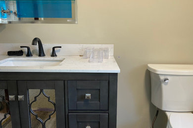 Small master vinyl floor, gray floor and single-sink bathroom photo in Boston with glass-front cabinets, black cabinets, a two-piece toilet, white countertops and a freestanding vanity