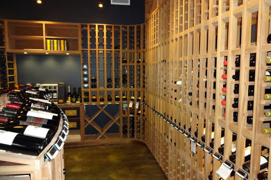 Foto på en mycket stor funkis vinkällare, med betonggolv och vinhyllor