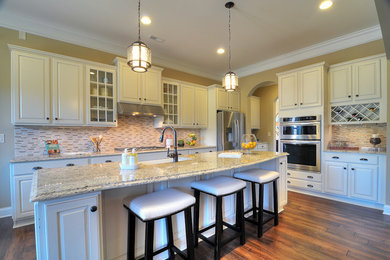 Inspiration for a contemporary medium tone wood floor kitchen remodel in Charlotte with a farmhouse sink, raised-panel cabinets, white cabinets, granite countertops, multicolored backsplash, stainless steel appliances and an island
