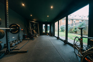 This is an example of a medium sized contemporary multi-use home gym in Surrey with black walls and feature lighting.