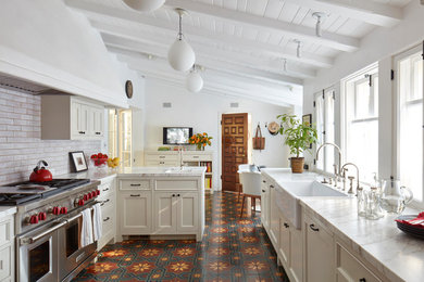 Inspiration for a mediterranean u-shaped ceramic tile and red floor eat-in kitchen remodel in Los Angeles with a farmhouse sink, shaker cabinets, beige cabinets, stainless steel appliances, a peninsula, white countertops and subway tile backsplash